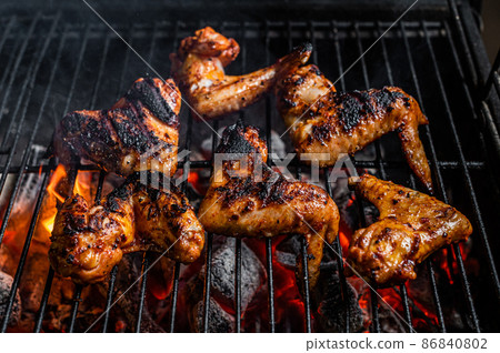 Chicken wings on barbecue, outdoor BBQ grill with fire. Top view 86840802