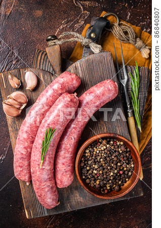 Bratwurst Raw meat sausages on wooden board with spices. Dark background. Top view 86840807