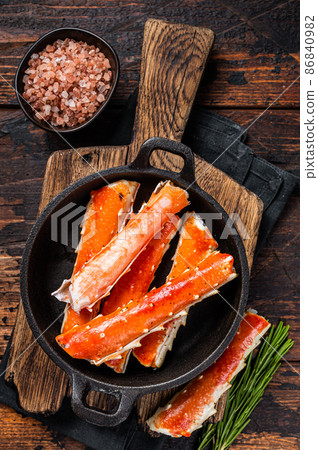 Alaskan King Crab legs Phalanx in a pan with herbs. Dark wooden background. Top view 86840982