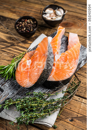 Raw Salmon steaks on a wooden cutting board with thyme and rosemary. wooden background. Top view Raw Salmon steaks on a wooden cutting board with thyme and rosemary. wooden background. Top view 86840994