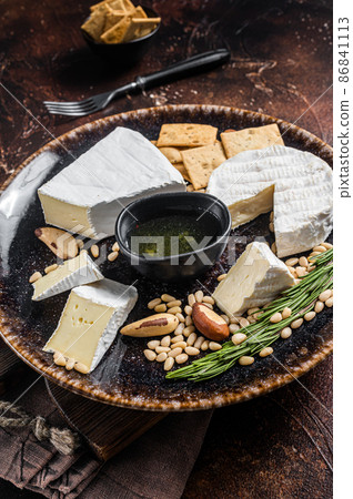 Cheese plate with brie and camembert on rustic plate with nuts and honey. Dark background. Top view 86841113