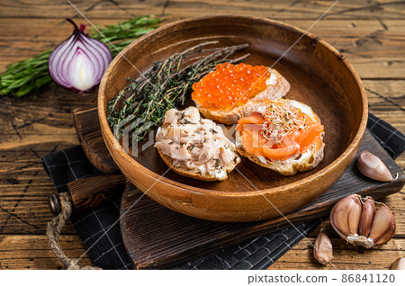 Bruschetta with Hot Smoked salmon, red caviar and herbs. Wooden background. Top view Bruschetta with Hot Smoked salmon, red caviar and herbs. Wooden background. Top view 86841120