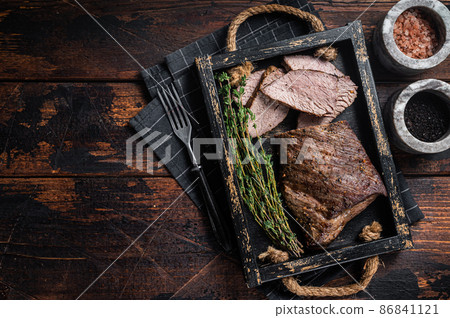 Grilled Tri Tip steak, sirloin bottom beef in a tray with herbs. Wooden background. Top view. Copy space 86841121