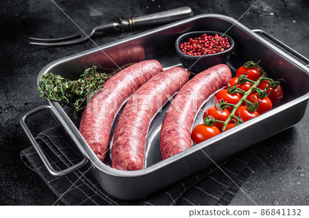 Uncooked Raw lamb and beef meat sausages in kitchen tray with herbs. Black background. Top view 86841132