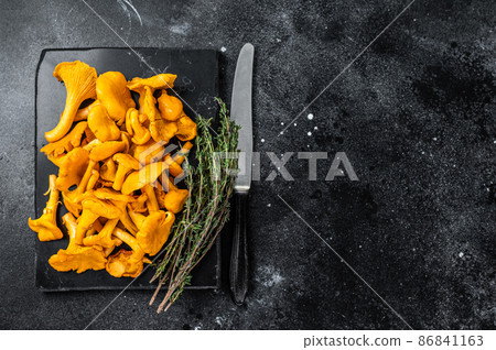Raw wild Chanterelles mushrooms on a marble board. Black background. Top view. Copy space 86841163