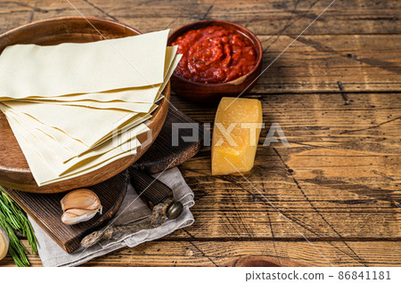 Set of ingredients for cooking lasagna close-up of Tomato sauce, pasta, cheese. wooden background. Top view. Copy space 86841181