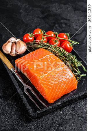 Protein vegetarian diet - raw salmon fillet steak with herbs and tomato. Black background. Top view 86841289