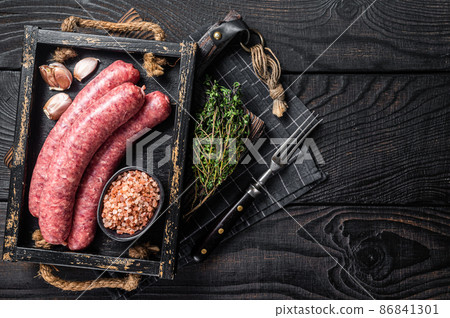 Raw sausages Bratwurst, fresh meat in wooden tray with thyme. Wooden background. Top view. Copy space 86841301