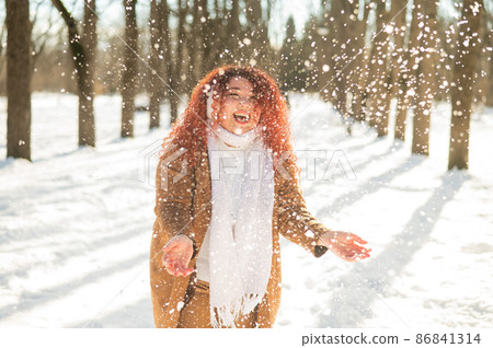 Fat caucasian woman playing snowballs in the park.  86841314