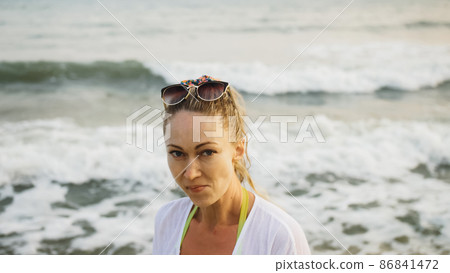 Close up portrait woman in a white tunic shirt on beach, near st Close up portrait woman in a white tunic shirt on beach, near st 86841472