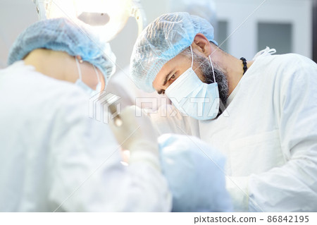 Surgeon and nurse during a dental operation. Anesthetized patient in the operating room. Installation of dental implants in the clinic. 86842195