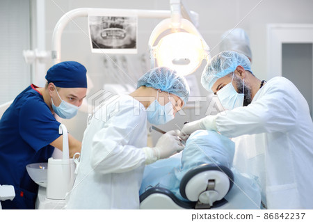 Surgeon and nurse during a dental operation. Anesthetized patient in the operating room. Installation of dental implants in the clinic. 86842237