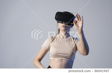 VR, augmented reality, science, future technology concept. Young brunette woman in glasses of virtual reality in neon light. Futuristic 3d glasses with virtual projection. 86842487