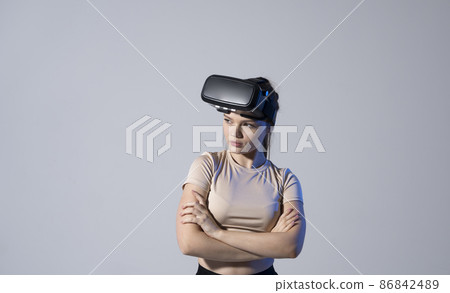 Young woman wearing a virtual reality headset goggles and playing a game with a friends. Future technology concept. 86842489