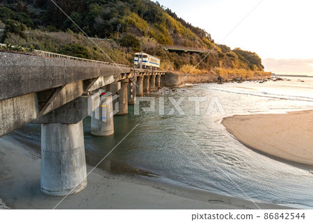 Nichinan Line White Kiha 40 在日向南部太平洋上空的橙色日出中沿著岩石海岸線行駛 86842544