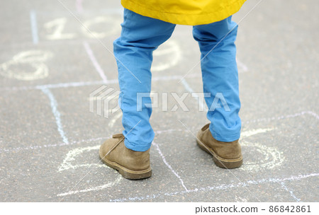Little boy's legs and hopscotch drawn on asphalt. Child playing hopscotch game on playground on spring day. Little boy's legs and hopscotch drawn on asphalt. Child playing hopscotch game on playground on spring day. 86842861