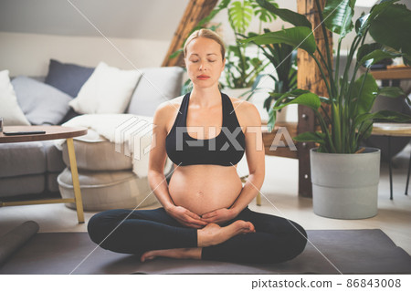 Young beautiful pregnant woman training yoga, caressing her belly. Young happy expectant relaxing, thinking about her baby and enjoying her future life. Motherhood, pregnancy, yoga concept. Young beautiful pregnant woman training yoga, caressing her belly. Young happy expectant relaxing, thinking about her baby and enjoying her future life. Motherhood, pregnancy, yoga concept. 86843008