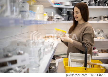 Smiling female housewife choosing straw basket container for interior decor space organizing Smiling female housewife choosing straw basket container for interior decor space organizing 86843655