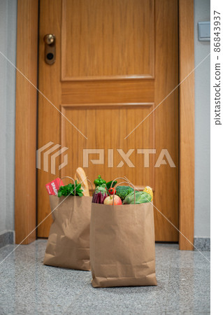 Food shopping bags stand at the door of the house or apartment. Vegetables and fruits delivery during quarantine and self-isolation. 86843937