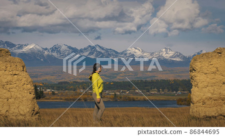 The woman in yellow green sportswear near old stone enjoying hig The woman in yellow green sportswear near old stone enjoying hig 86844695