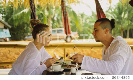 Man and woman eat and drink tasty beverages spending time in traditional local floating cafe on water. Loving happy couple having breakfast outdoors Man and woman eat and drink tasty beverages spending time in traditional local floating cafe on water. Loving happy couple having breakfast outdoors 86844865