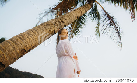 Woman in a white tunic shirt on beach, near stormy sea, tilted p Woman in a white tunic shirt on beach, near stormy sea, tilted p 86844870
