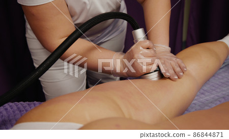 Woman receiving anti-ageing anti-cellulite massage vacuum rf lifting in spa salon. Wellness body and skin care. Woman receiving anti-ageing anti-cellulite massage vacuum rf lifting in spa salon. Wellness body and skin care. 86844871