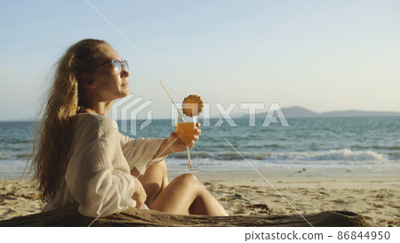 Woman sitting in white dress drinks pineapple cocktail Pina Cola Woman sitting in white dress drinks pineapple cocktail Pina Cola 86844950