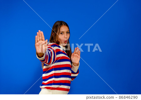 Caucasian brunette girl in striped pullover against blue wall Ready to fight with fist defense gesture, funny face, not afraid of problem Caucasian brunette girl in striped pullover against blue wall Ready to fight with fist defense gesture, funny face, not afraid of problem 86846290