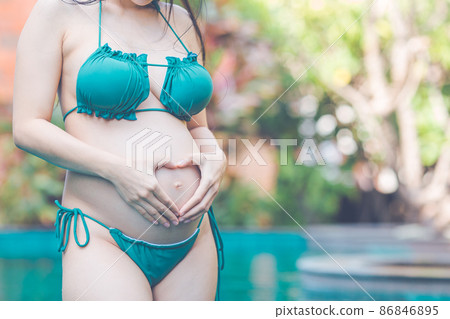 Beautiful pregnant woman at the summer swimming pool with bikini. 86846895