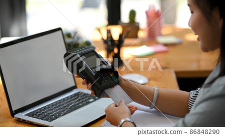 A female hotel receptionist insert a credit card to pay a customer's the bill 86848290