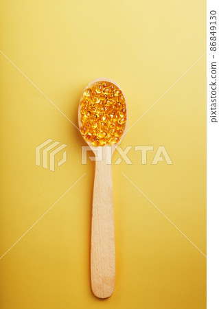 Vitamin D3 Capsules in a spoon with other vitamin D3 capsules around them on a yellow background Vitamin D3 Capsules in a spoon with other vitamin D3 capsules around them on a yellow background 86849130