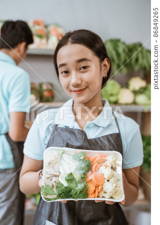Smiling veggie saleswoman showing vegetables in a wrap Smiling veggie saleswoman showing vegetables in a wrap 86849265