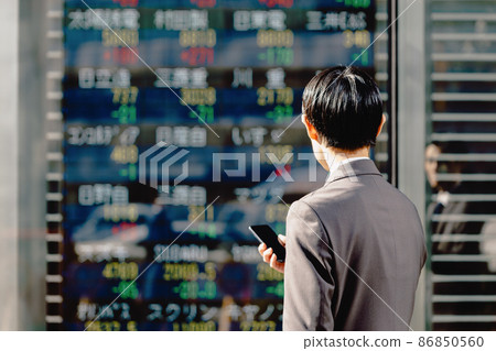 A man looking at a stock board (holding a smartphone) 86850560