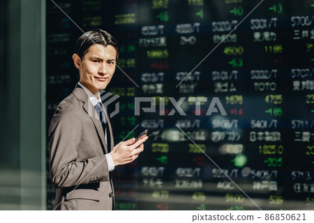 A man looking at a stock board (holding a smartphone) A man looking at a stock board (holding a smartphone) 86850621