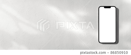 A smartphone placed in a white space with sunlight through the trees 86850910