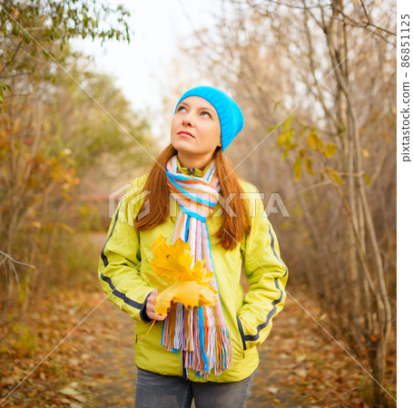 Young woman walking in the fall season. Autumn outdoor portrait Young woman walking in the fall season. Autumn outdoor portrait 86851125