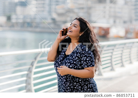 An Indian girl walks along the embankment and talks on the phone. 86853711