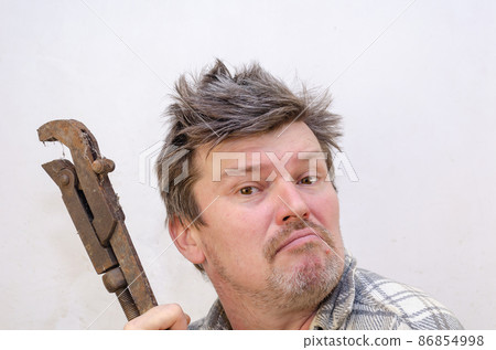 Portrait of a funny geezer with a rusty old dirty pipe wrench. Portrait of a funny geezer with a rusty old dirty pipe wrench. 86854998