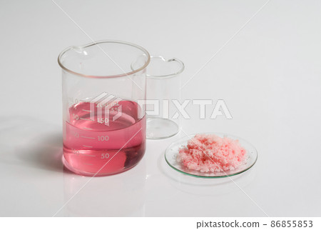 Close up inorganic chemical on white laboratory table. Pink flake chemicals in Chemical Watch Glass place next to Red EPOXY liquid rasin in beaker. Close up inorganic chemical on white laboratory table. Pink flake chemicals in Chemical Watch Glass place next to Red EPOXY liquid rasin in beaker. 86855853
