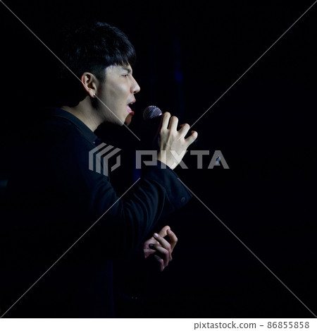 Young black-haired asian singer with a microphone singing on stage. The atmosphere at night in the pub 86855858