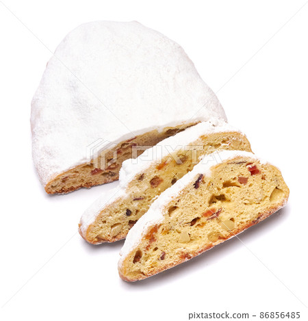 Sliced Traditional Christmas stollen cake with marzipan and dried fruit isolated on white background 86856485