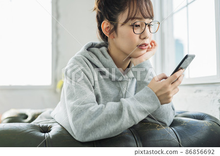 A woman who uses a smartphone at home 86856692