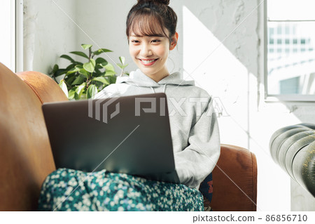 一個女人在家裡的沙發上使用電腦 一個女人在家裡的沙發上使用電腦 86856710