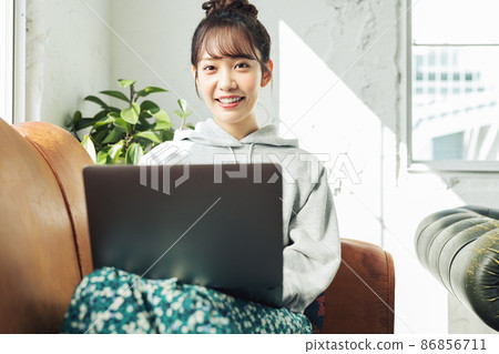 一個女人在家裡的沙發上使用電腦 一個女人在家裡的沙發上使用電腦 86856711
