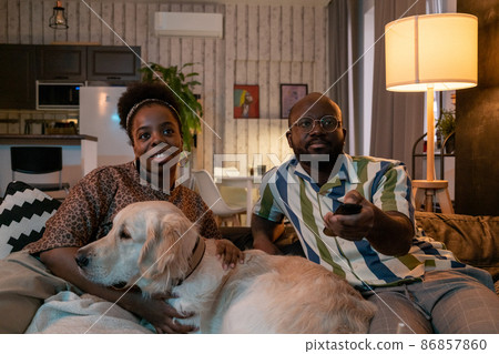 African couple with dog watching TV African couple with dog watching TV 86857860