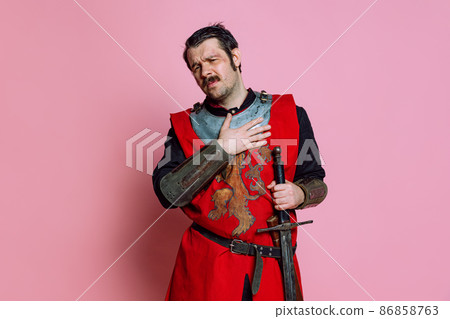 One young man, medieval warrior or knight wearing wearing armor clothing posing isolated over pink background. Comparison of eras, history, emotions One young man, medieval warrior or knight wearing wearing armor clothing posing isolated over pink background. Comparison of eras, history, emotions 86858763
