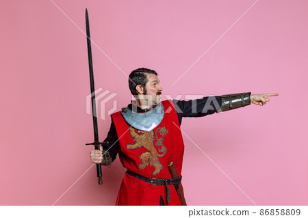 Comic portrait of medieval warrior or knight wearing wearing armor clothing holding big sword isolated over pink background. Comparison of eras, history 86858809