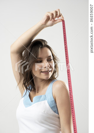 Young brunette fitness sporty sexy woman with pink measure tape on white background. Time for diet and slimming weight loss. Health care and healthy nutrition. 86859007