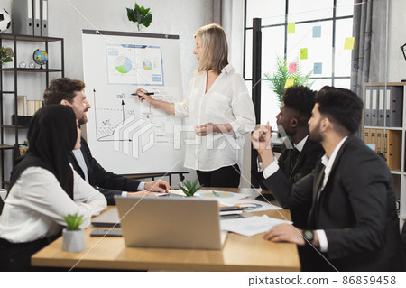 Aged woman presenting financial report to diverse partners 86859458